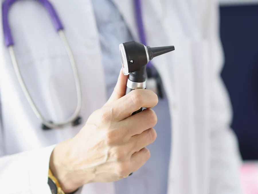 Médico segurando um otoscópio durante consulta audiológica