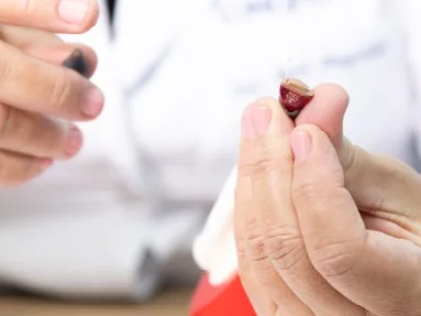 Mãos segurando um aparelho auditivo intra-auricular